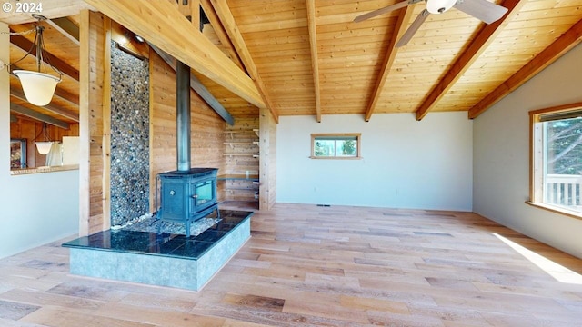 unfurnished living room featuring a wood stove, wooden walls, light hardwood / wood-style flooring, vaulted ceiling with beams, and wood ceiling