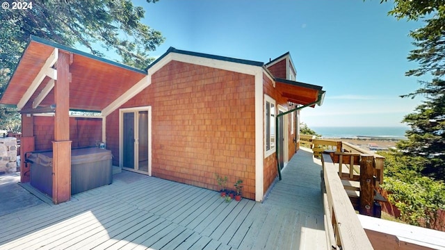 deck featuring a water view and a hot tub