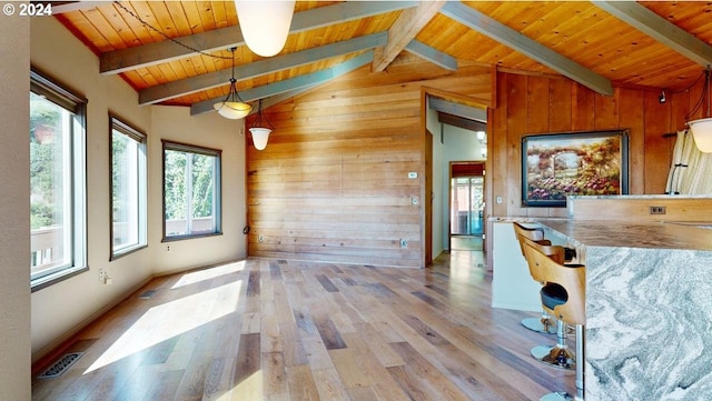 unfurnished dining area featuring lofted ceiling with beams, light hardwood / wood-style floors, wooden ceiling, and wood walls