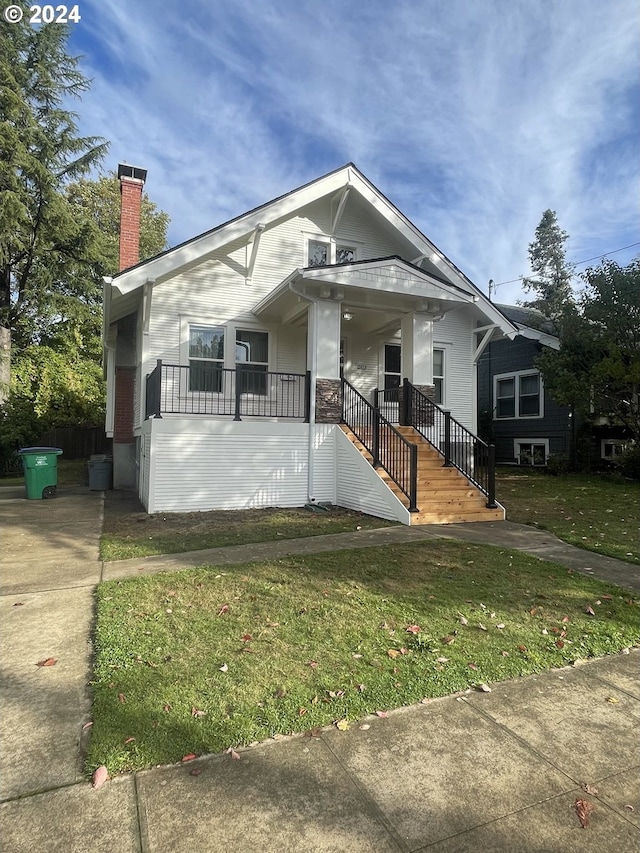 bungalow featuring a porch and a front lawn