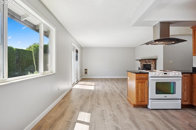 kitchen featuring light wood-type flooring, electric stove, island range hood, and a textured ceiling