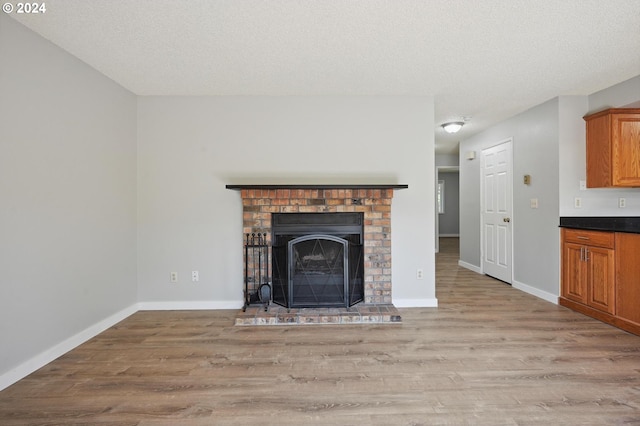 unfurnished living room featuring a fireplace, a textured ceiling, and light hardwood / wood-style flooring