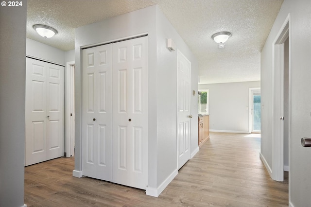 corridor featuring a textured ceiling and light hardwood / wood-style flooring