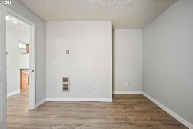 spare room featuring hardwood / wood-style flooring, heating unit, and a textured ceiling