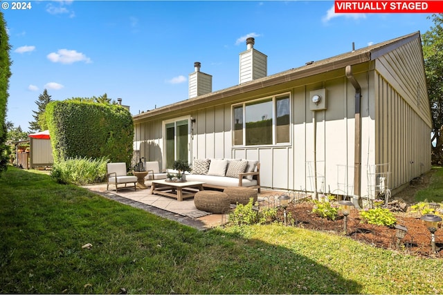 rear view of property with a yard, an outdoor hangout area, a patio area, and a storage unit