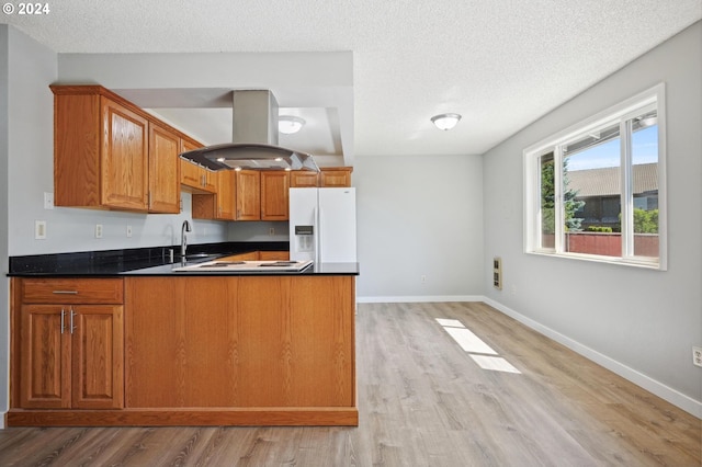 kitchen featuring a textured ceiling, white appliances, light hardwood / wood-style flooring, island range hood, and kitchen peninsula