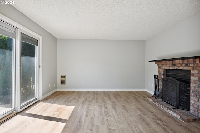 unfurnished living room with hardwood / wood-style flooring, a textured ceiling, a brick fireplace, and heating unit