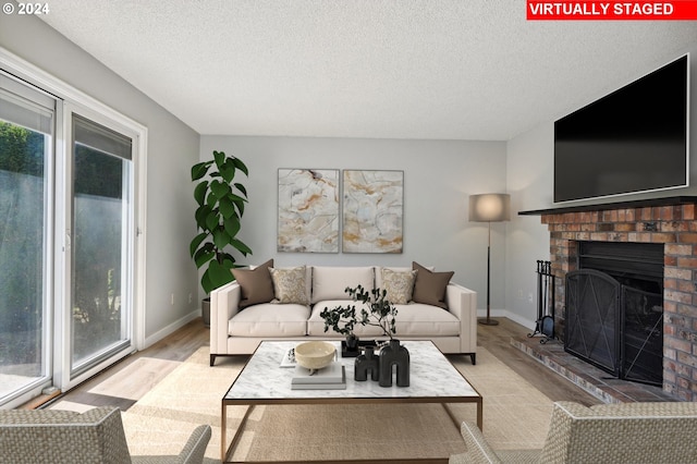 living room with a fireplace, a textured ceiling, and light hardwood / wood-style flooring