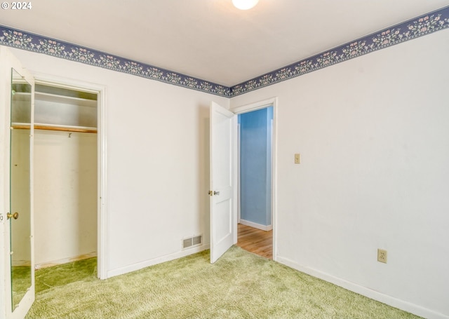 unfurnished bedroom with a closet and light colored carpet