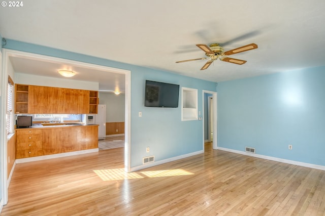 unfurnished living room with light hardwood / wood-style floors, sink, and ceiling fan