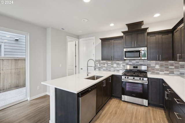 kitchen featuring light hardwood / wood-style floors, kitchen peninsula, sink, and appliances with stainless steel finishes