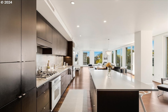 kitchen featuring a large island, dark hardwood / wood-style floors, oven, and stainless steel gas cooktop