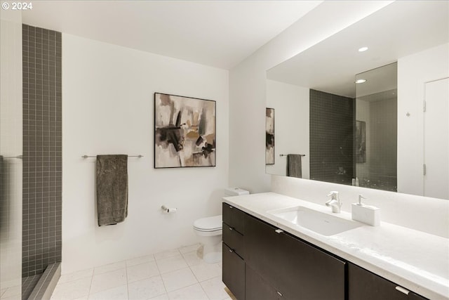 bathroom featuring tile patterned flooring, vanity, toilet, and tiled shower