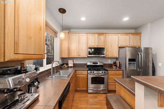 kitchen with sink, tile countertops, light hardwood / wood-style flooring, appliances with stainless steel finishes, and pendant lighting