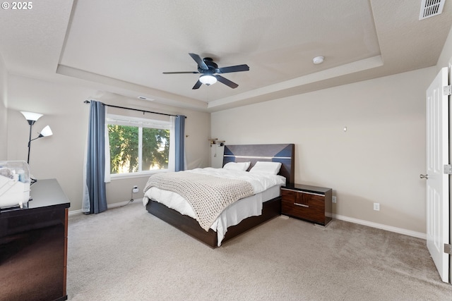 bedroom featuring light colored carpet, ceiling fan, and a tray ceiling