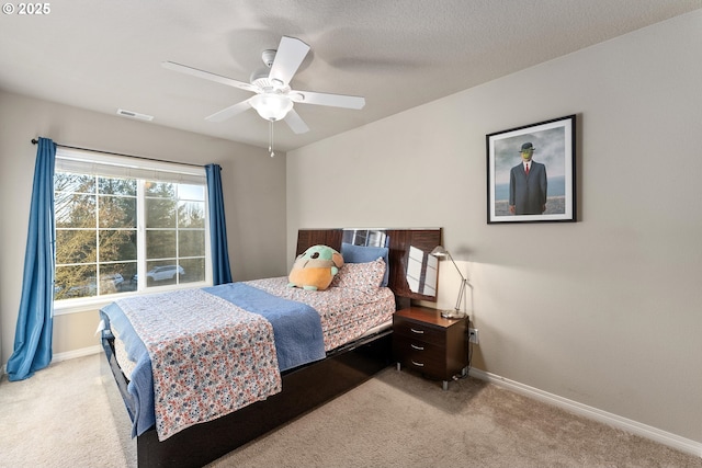 bedroom with ceiling fan, light colored carpet, and a textured ceiling