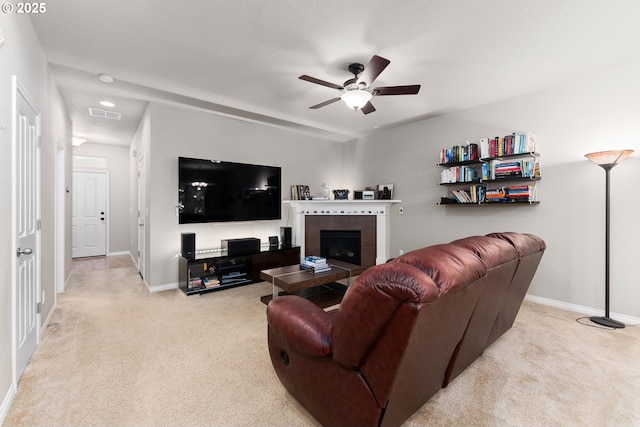 living room featuring a tiled fireplace, light carpet, and ceiling fan