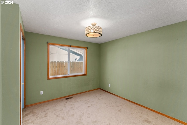 carpeted empty room featuring a textured ceiling