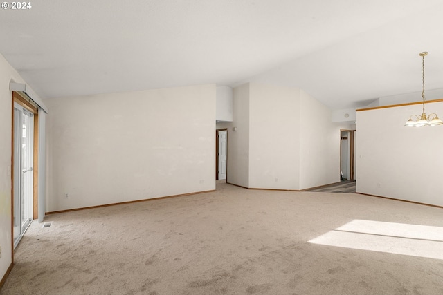 carpeted empty room featuring vaulted ceiling and a notable chandelier