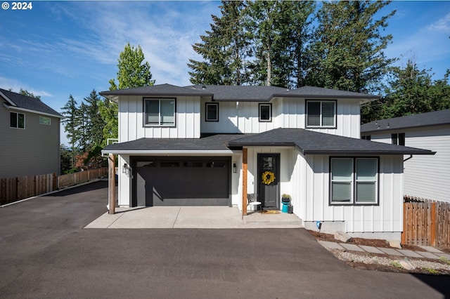 view of front of house with board and batten siding, aphalt driveway, an attached garage, and fence
