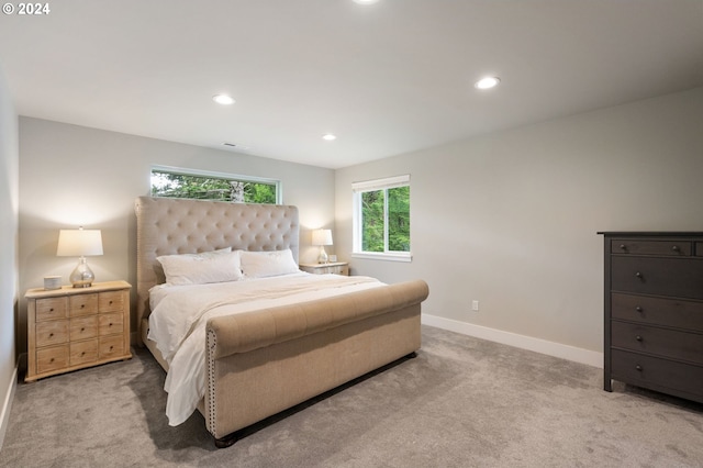 bedroom with multiple windows, light carpet, and baseboards