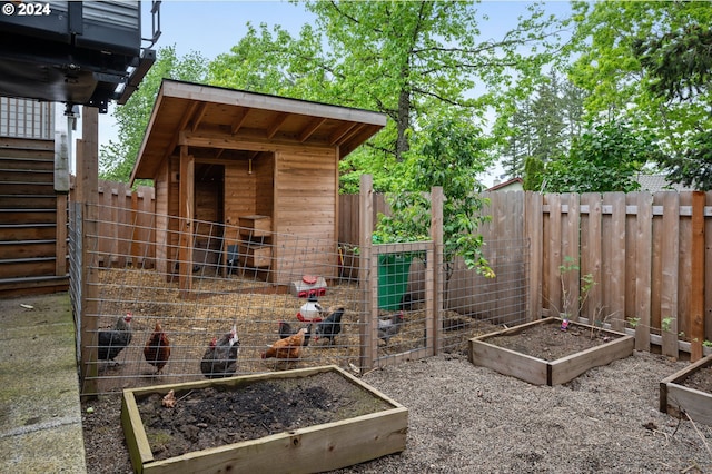 view of playground with exterior structure, an outdoor structure, a garden, and a fenced backyard