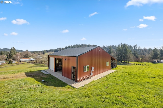 view of side of home featuring a garage, an outbuilding, and a lawn