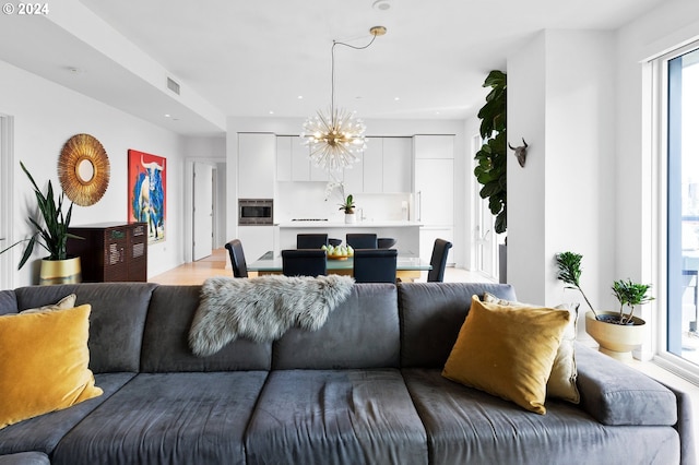 living room with light wood-type flooring, visible vents, a notable chandelier, and recessed lighting