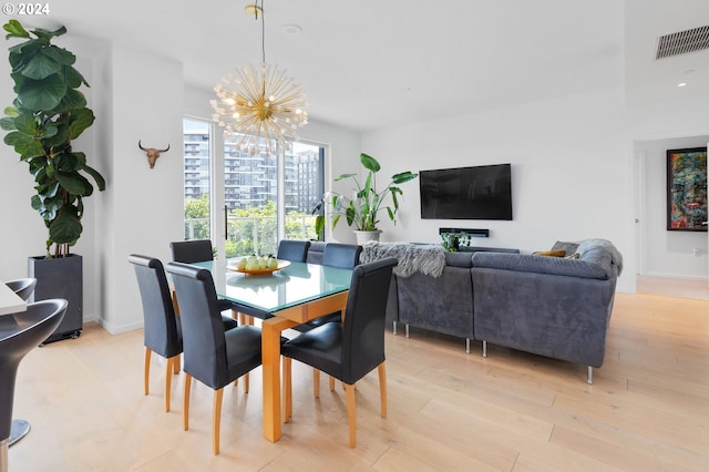 dining space with an inviting chandelier and light hardwood / wood-style flooring