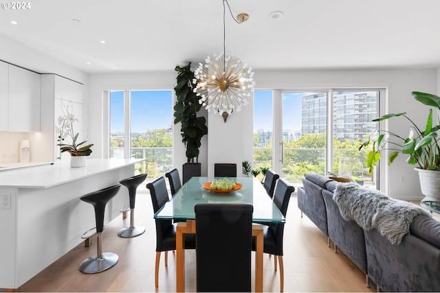 dining area with light hardwood / wood-style flooring and an inviting chandelier