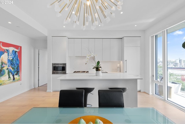 kitchen with white cabinets, light countertops, stainless steel microwave, modern cabinets, and pendant lighting