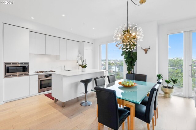 dining space with light wood-type flooring, a healthy amount of sunlight, and a chandelier