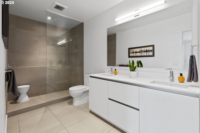 bathroom with vanity, toilet, tiled shower, and tile patterned flooring