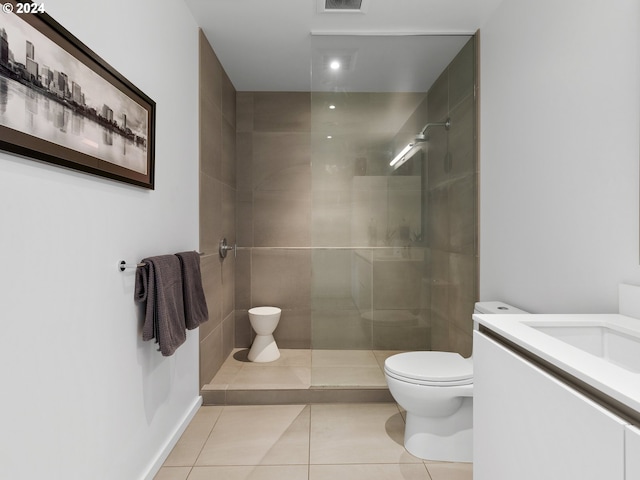 bathroom with vanity, toilet, tiled shower, and tile patterned flooring