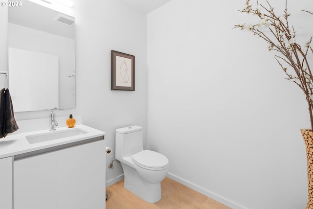 bathroom with baseboards, visible vents, toilet, wood finished floors, and vanity