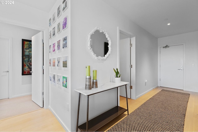 hall featuring light wood-type flooring, baseboards, and recessed lighting