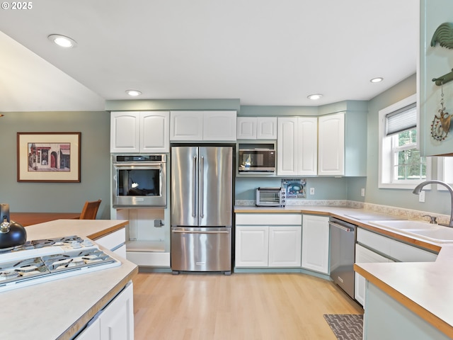 kitchen featuring sink, light wood-type flooring, white cabinets, and appliances with stainless steel finishes