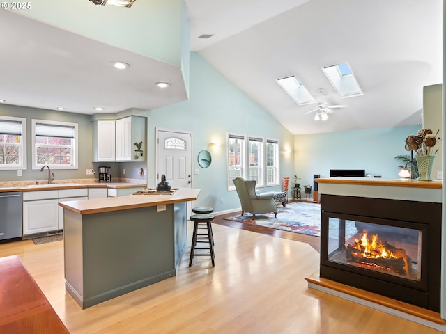 kitchen with a breakfast bar area, stainless steel dishwasher, white cabinets, and a skylight