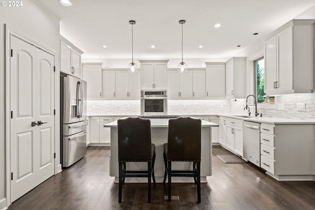 kitchen featuring dark wood-type flooring, a center island, decorative light fixtures, white cabinetry, and appliances with stainless steel finishes