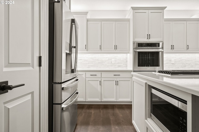 kitchen featuring appliances with stainless steel finishes, white cabinetry, light stone counters, and dark hardwood / wood-style floors