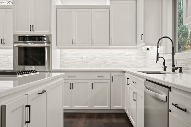 kitchen with stainless steel appliances, backsplash, sink, white cabinetry, and dark hardwood / wood-style flooring