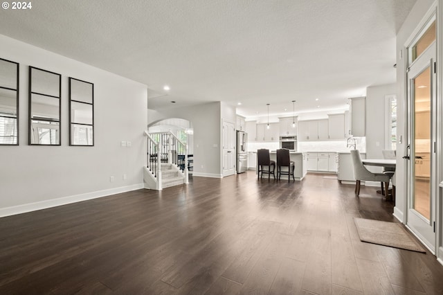 living room with a textured ceiling and dark hardwood / wood-style floors