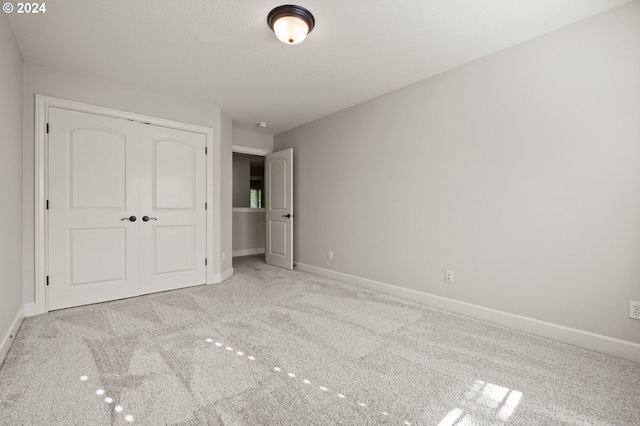 unfurnished bedroom with light carpet and a closet