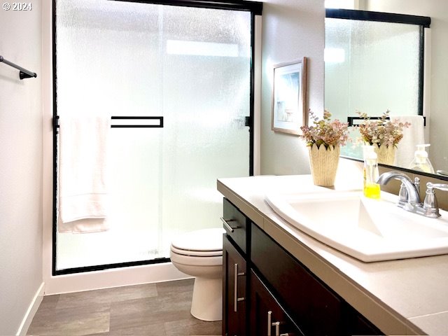 bathroom featuring vanity, toilet, hardwood / wood-style floors, and an enclosed shower