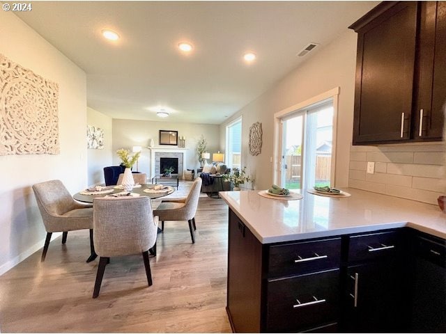 kitchen featuring light wood-type flooring, dark brown cabinets, and decorative backsplash