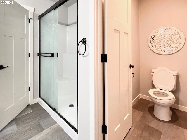 bathroom with toilet and a shower with shower door