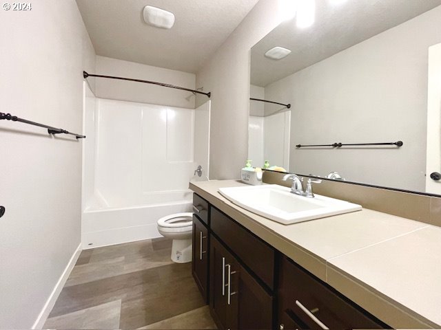 full bathroom featuring vanity, toilet, hardwood / wood-style floors, and shower / tub combination