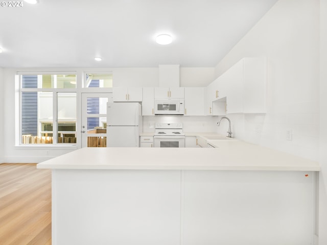 kitchen with white appliances, sink, light wood-type flooring, kitchen peninsula, and white cabinetry