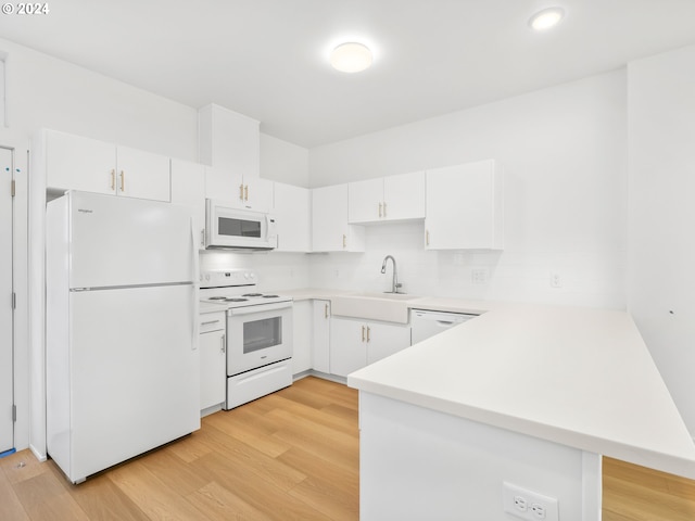 kitchen with white appliances, sink, kitchen peninsula, white cabinetry, and light hardwood / wood-style flooring