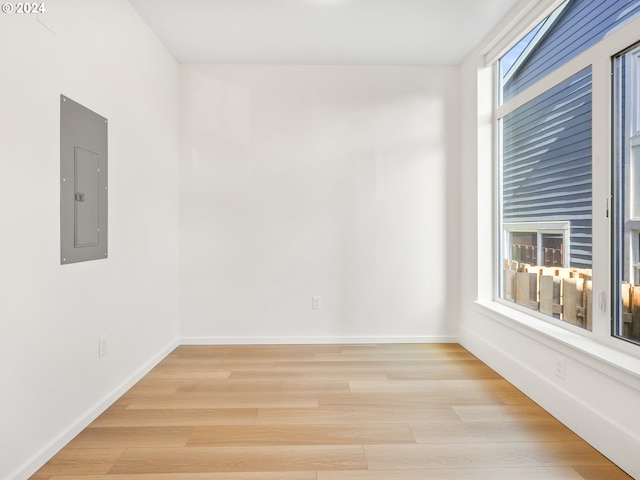 unfurnished room with electric panel and light wood-type flooring